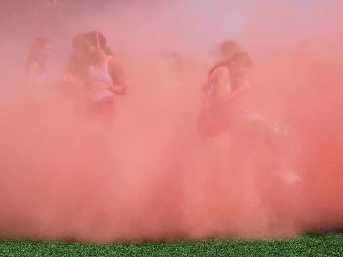 Upper School students navigate within the cloud of red powder during the annual color war at Derby Day. 