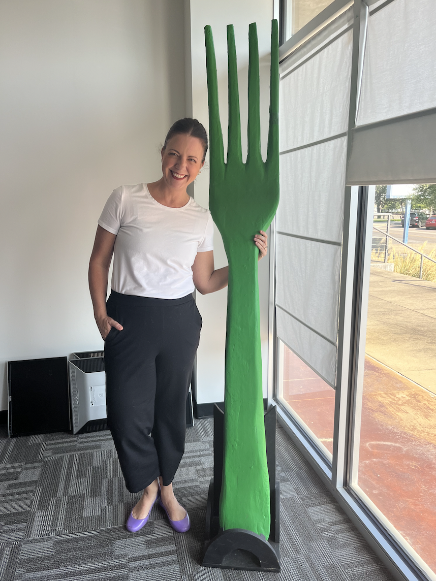 Project Green Fork team member Leanne Edwards stands next to giant green fork.